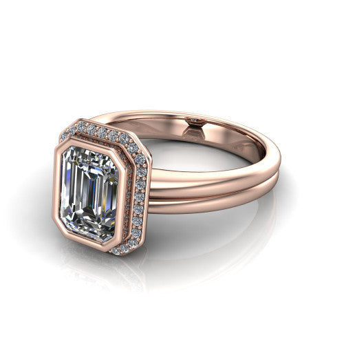 Maggie emerald halo engagement ring in 18K Rose Gold, three-quarter perspective showing the bezel-set center framed by a pav&eacute; halo on a polished double-rail shank