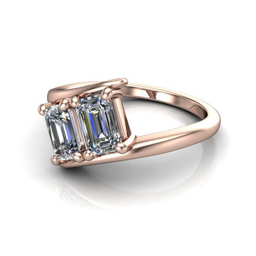 Alayna emerald three stone engagement ring in 18K Rose Gold, three-quarter perspective showing two diamonds set diagonally in claw baskets on a polished bypass swirl shank