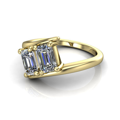 Alayna emerald three stone engagement ring in 18K Yellow Gold, three-quarter perspective showing two diamonds set diagonally in claw baskets on a polished bypass swirl shank