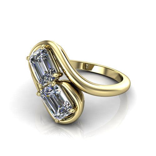 Daniela emerald three stone engagement ring in 14K Yellow Gold, three-quarter perspective showing two emerald cut diamonds half-bezel set diagonally on a polished bypass shank