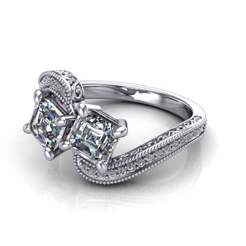 Stevie square emerald three stone engagement ring in Platinum, three-quarter perspective showing two step-cut square emerald diamonds set diagonally on filigree shoulders with milgrain edges and a pave center band