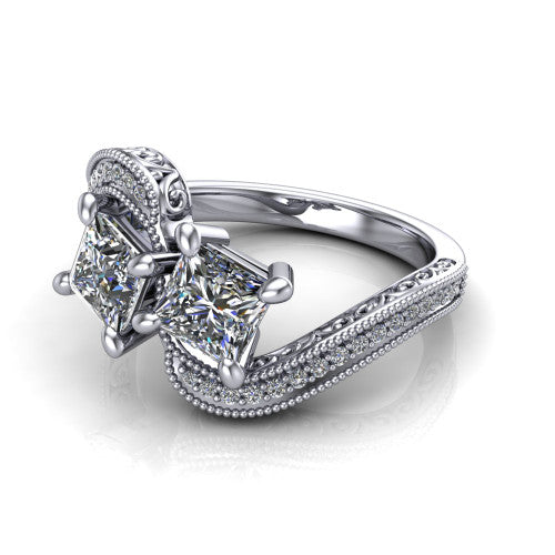 Stevie princess three stone engagement ring in Platinum, three-quarter perspective showing two brilliant princess-cut diamonds set diagonally on filigree shoulders with milgrain edges and a pave center band