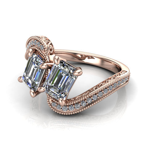 Stevie emerald three stone engagement ring in 14K Rose Gold, three-quarter perspective showing two step-cut emerald diamonds set diagonally on filigree shoulders with milgrain edges and a pave center band