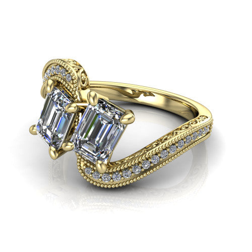 Stevie emerald three stone engagement ring in 14K Yellow Gold, three-quarter perspective showing two step-cut emerald diamonds set diagonally on filigree shoulders with milgrain edges and a pave center band