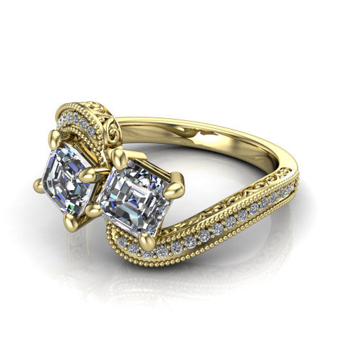 Stevie square emerald three stone engagement ring in 14K Yellow Gold, three-quarter perspective showing two step-cut square emerald diamonds set diagonally on filigree shoulders with milgrain edges and a pave center band