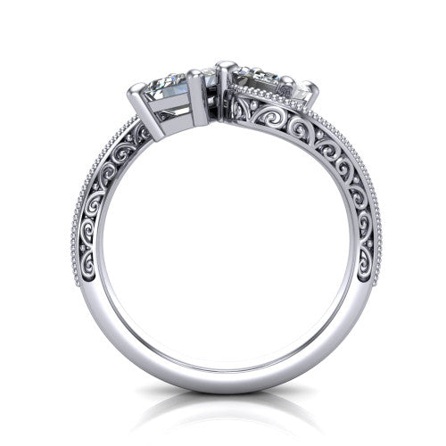 Stevie emerald three stone engagement ring in Platinum, through-finger front profile showing the two-stone head, filigree shoulders, milgrain band edges, and pave center row