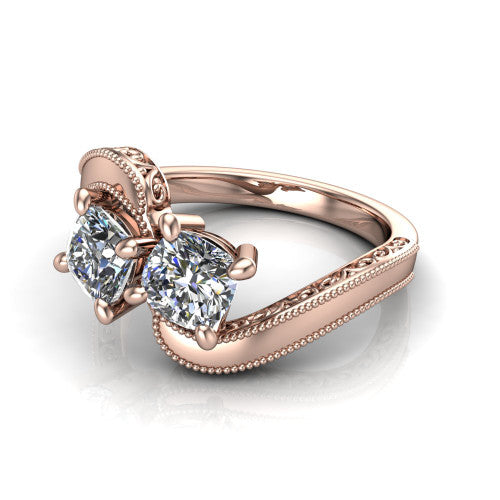 Logan cushion three stone engagement ring in 18K Rose Gold, three-quarter perspective showing two brilliant cushion-cut diamonds set diagonally on engraved filigree shoulders with milgrain edges