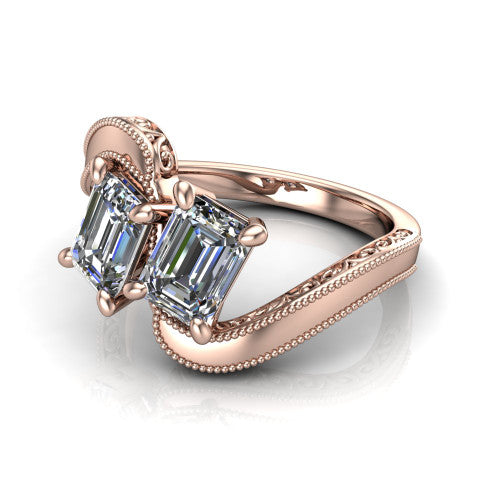 Logan emerald three stone engagement ring in 14K Rose Gold, three-quarter perspective showing two step-cut emerald diamonds set diagonally on engraved filigree shoulders with milgrain edges