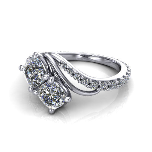 Gwen cushion three stone engagement ring in Platinum, three-quarter perspective showing two brilliant cushion-cut diamonds set diagonally on a pave wraparound shank with bypass curving shoulders