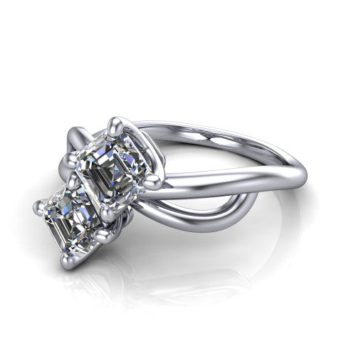 Mya square emerald three stone engagement ring in Platinum, three-quarter perspective showing two step-cut square emerald diamonds set diagonally on a polished infinity-loop shank