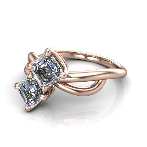 Mya square emerald three stone engagement ring in 14K Rose Gold, three-quarter perspective showing two step-cut square emerald diamonds set diagonally on a polished infinity-loop shank