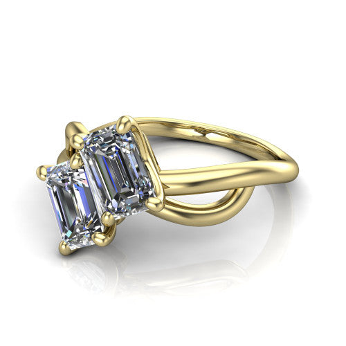 Mya emerald three stone engagement ring in 14K Yellow Gold, three-quarter perspective showing two step-cut emerald diamonds set diagonally on a polished infinity-loop shank