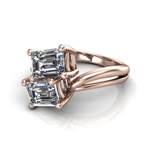 Lexi emerald three stone engagement ring in 18K Rose Gold, three-quarter perspective showing two step-cut emerald diamonds set diagonally on a bypass split shank with plain bands
