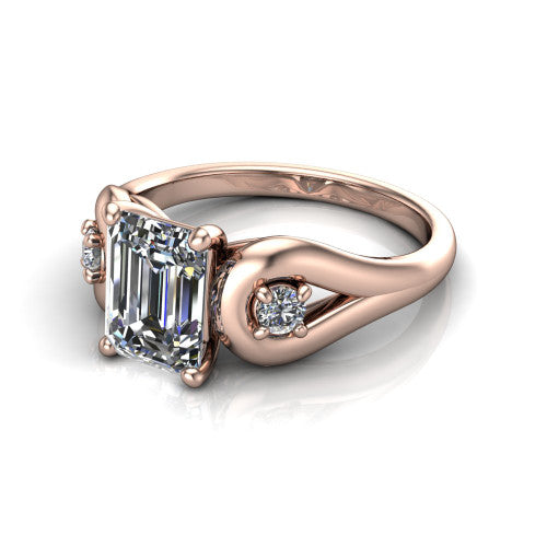 Imani emerald three stone engagement ring in 14K Rose Gold, three-quarter perspective showing the step-cut emerald center diamond flanked by two round side diamonds in square frames on bypass loop shoulders