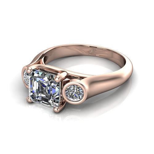 Rory square emerald three stone engagement ring in 14K Rose Gold, three-quarter perspective showing the square emerald center diamond between two bezel-set round side stones