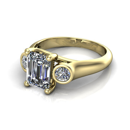 Rory emerald three stone engagement ring in 18K Yellow Gold, three-quarter perspective showing the emerald center diamond between two bezel-set round side stones